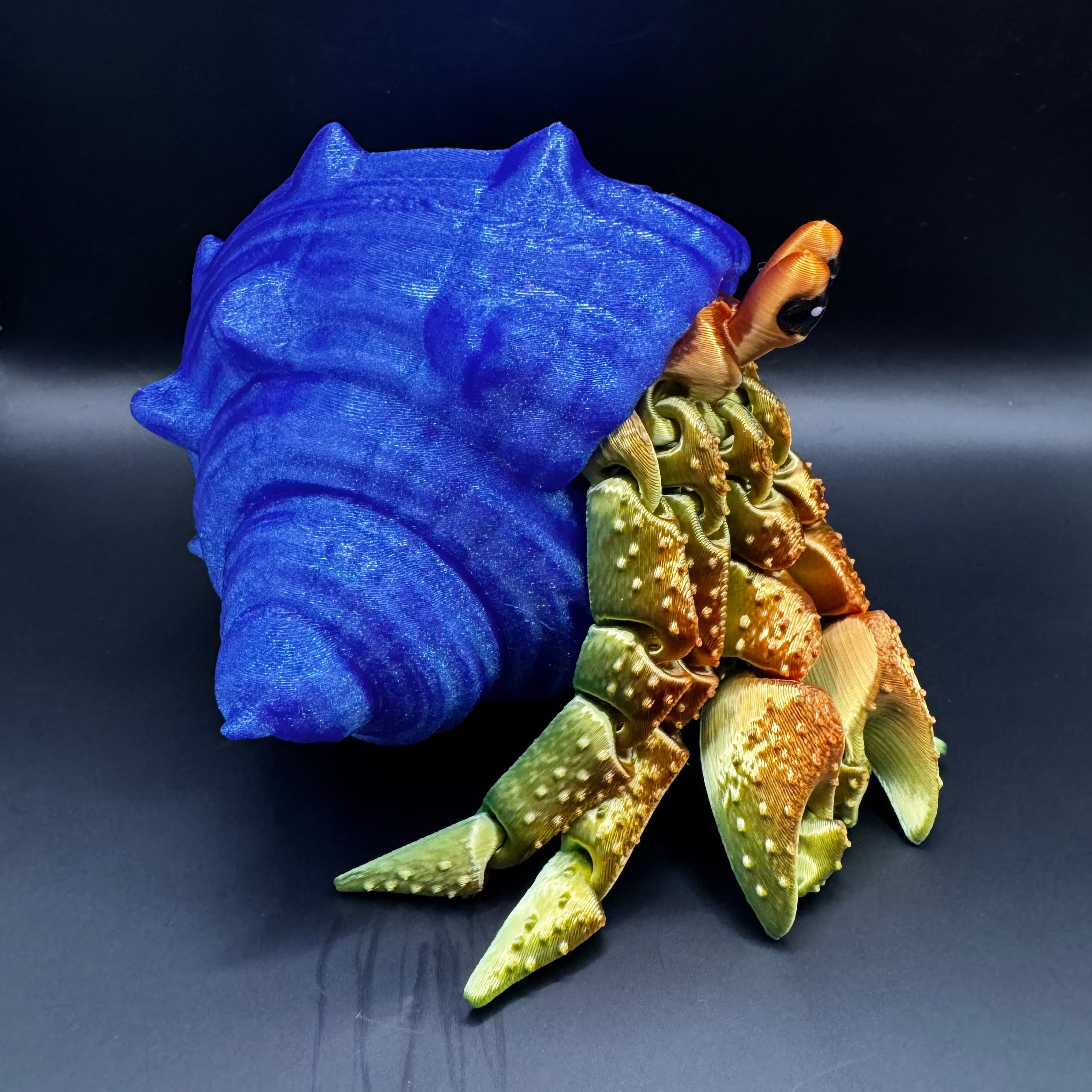 3d printed hermit crab with redish gold body inside a blue shell 