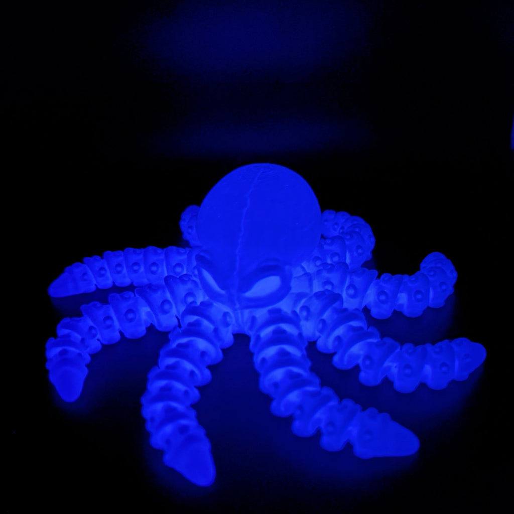 Ghost Current glow-in-the-dark octopus companion illuminated with a bright blue glow in a dark setting.