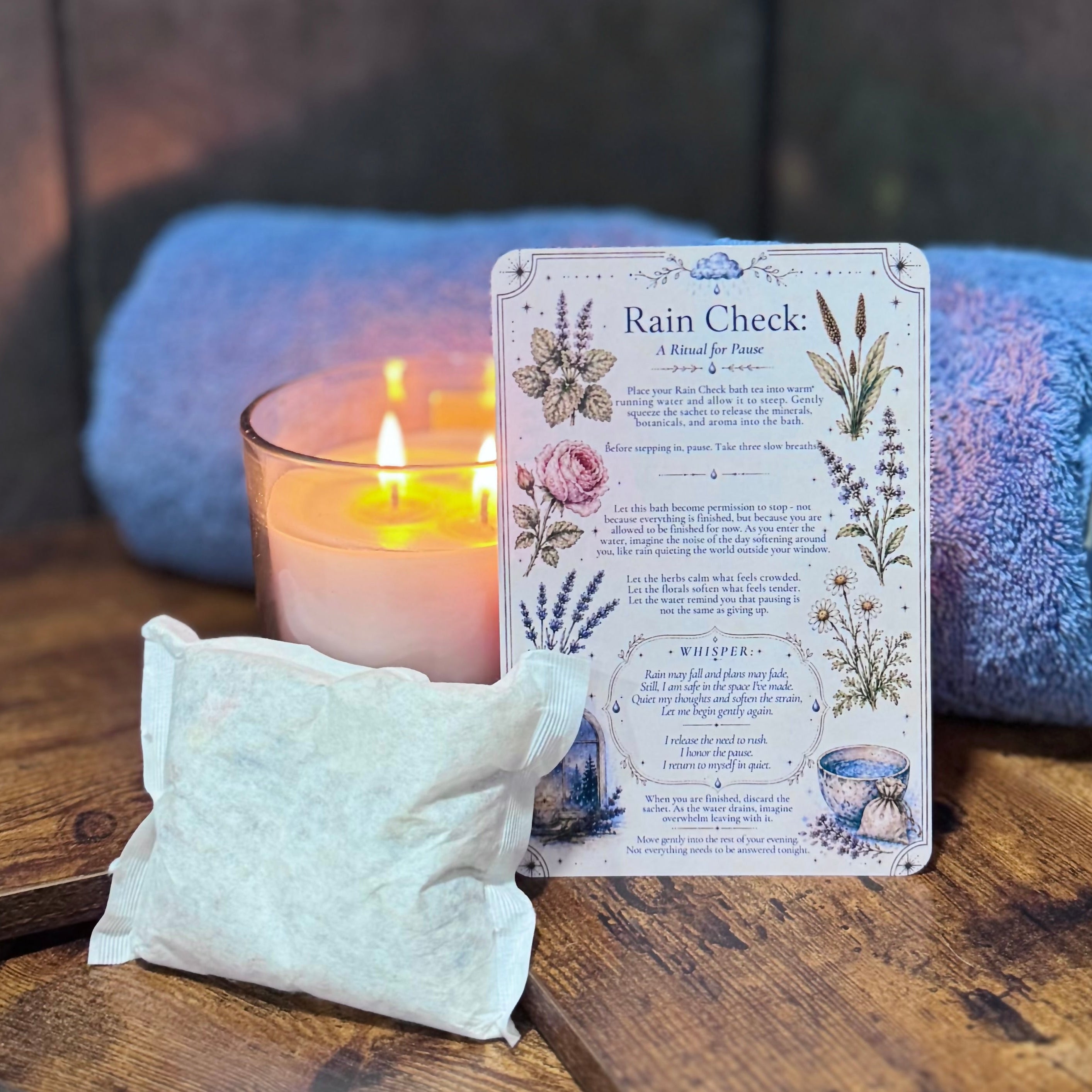 Candle, bath tea bag, and a ritual card on a wooden surface with a stone wall background