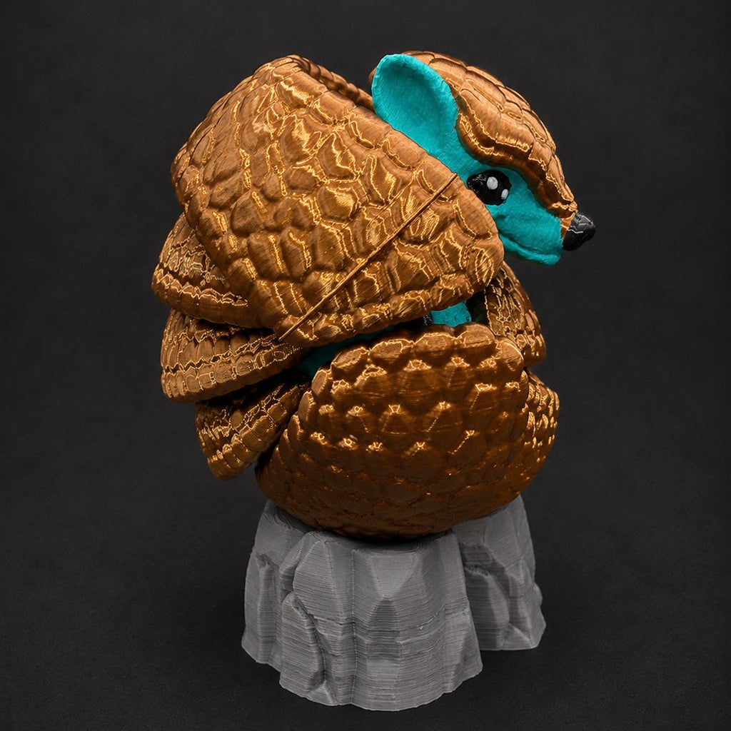 Side view of Burrow Bell curled on its included gray rock base with its turquoise face peeking through the bronze shell.