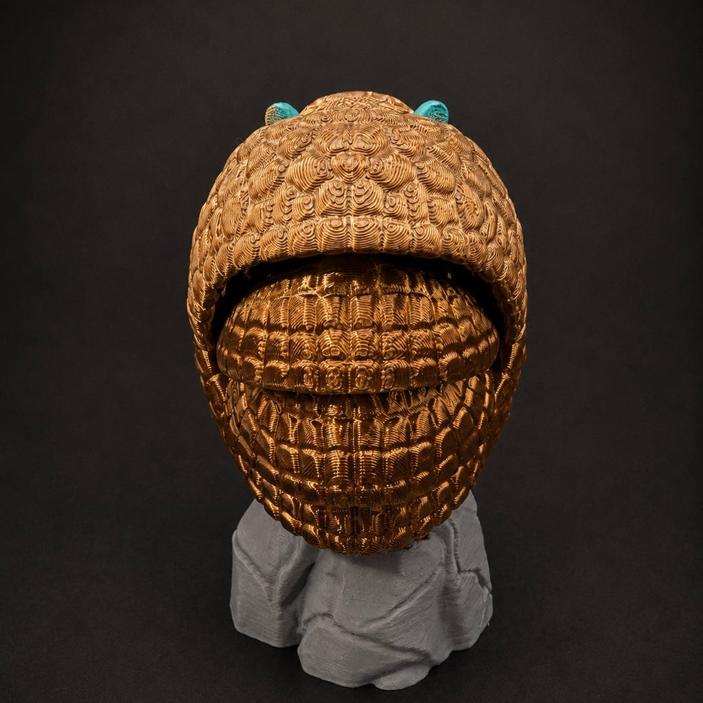 Rear view of Burrow Bell curled into a ball on its rock base, highlighting the detailed bronze shell.