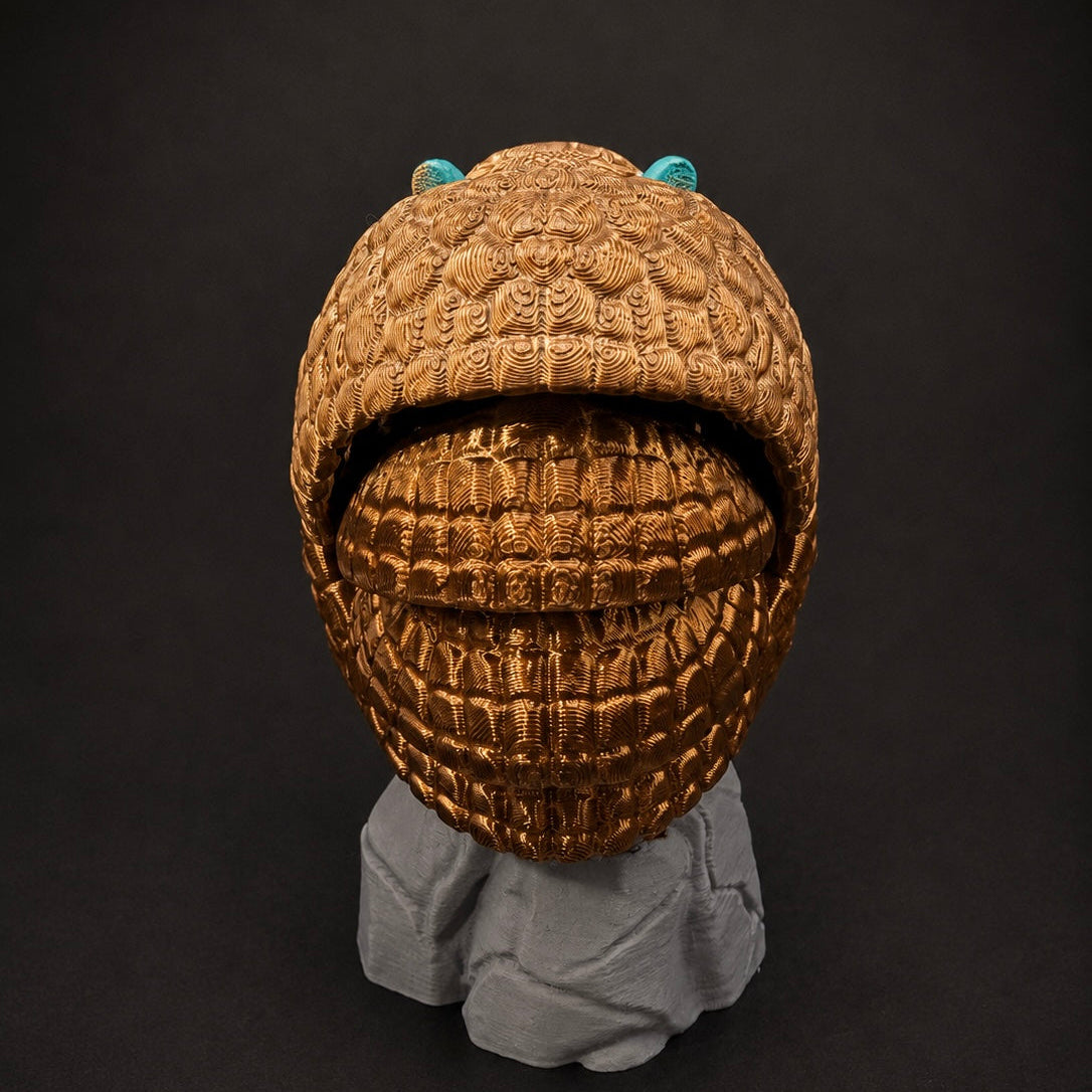 Rear view of Burrow Bell curled into a ball on its rock base, highlighting the detailed bronze shell.
