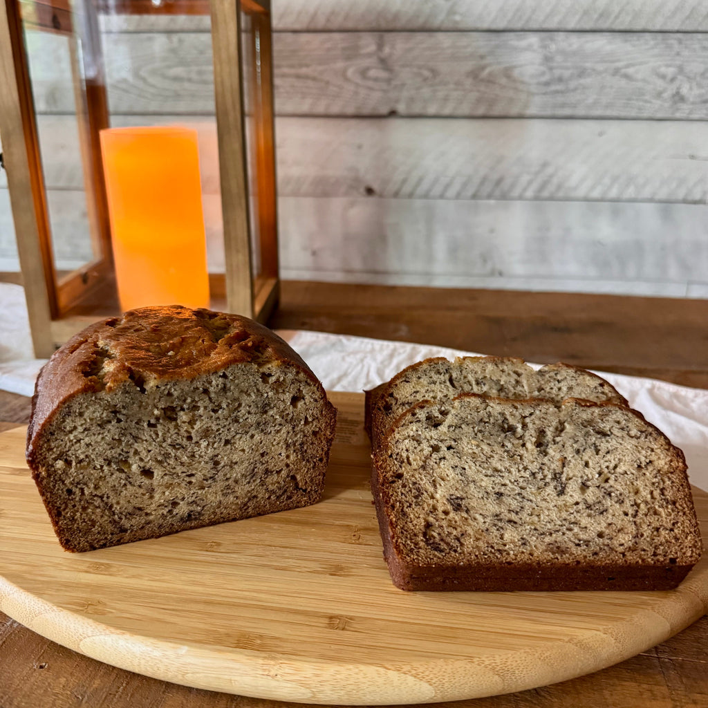 Classic banana bread loaf showing its golden, crackled top crust on a wooden serving board.