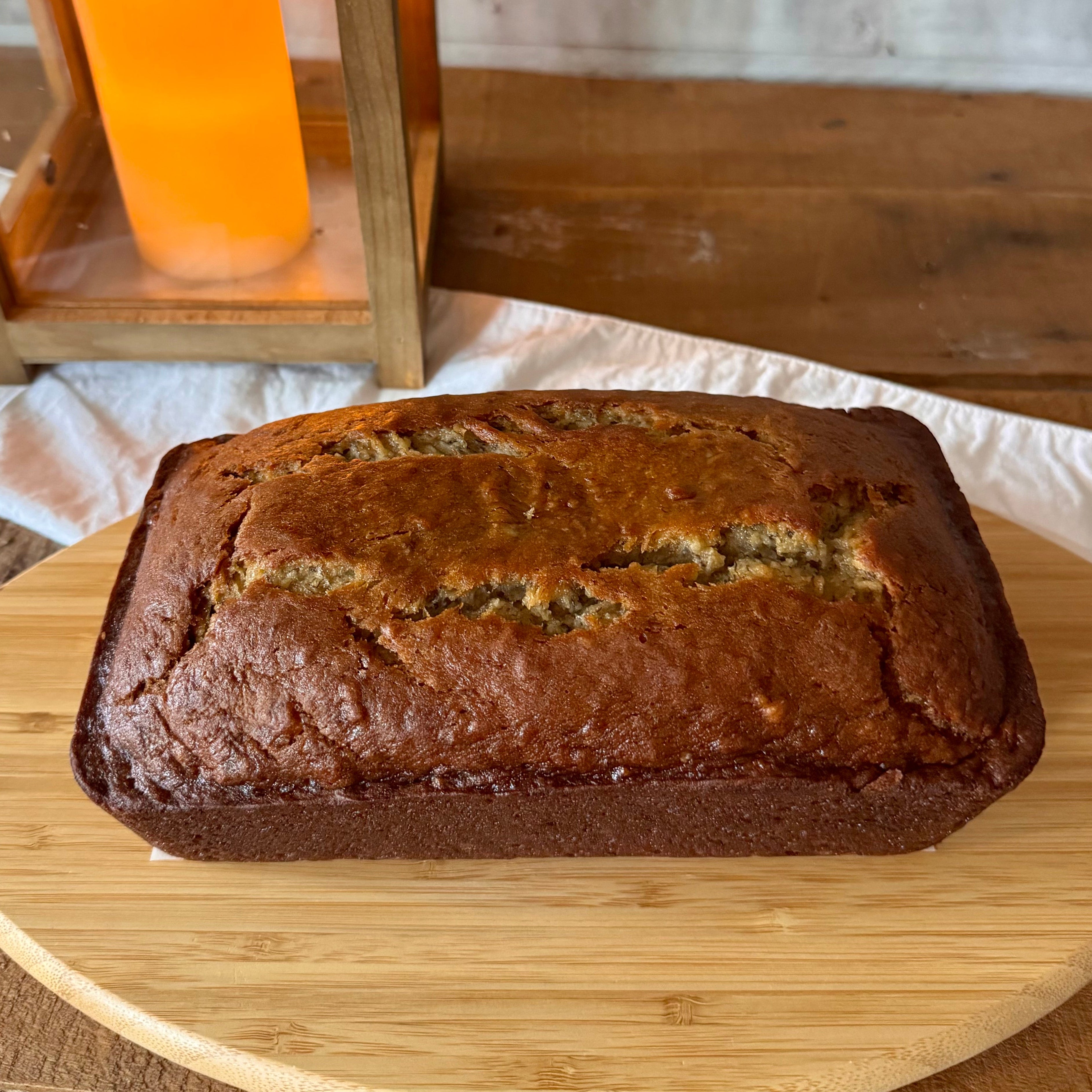 Classic banana bread loaf showing its golden, crackled top crust on a wooden serving board.