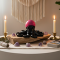 Glow in the dark resin octopus sculpture in black with pink glow head displayed in a warm meditation space