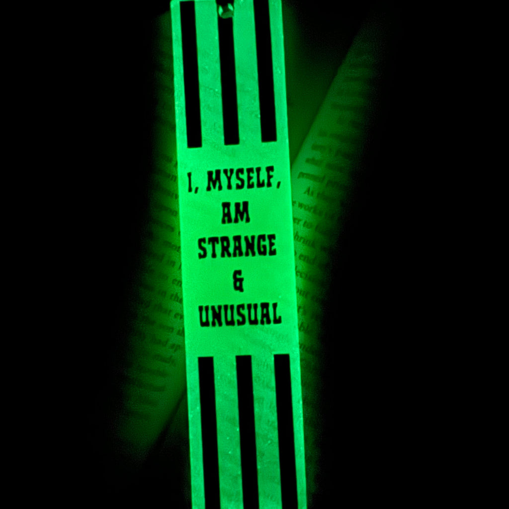 Glow in the dark green bookmark with text on a black background