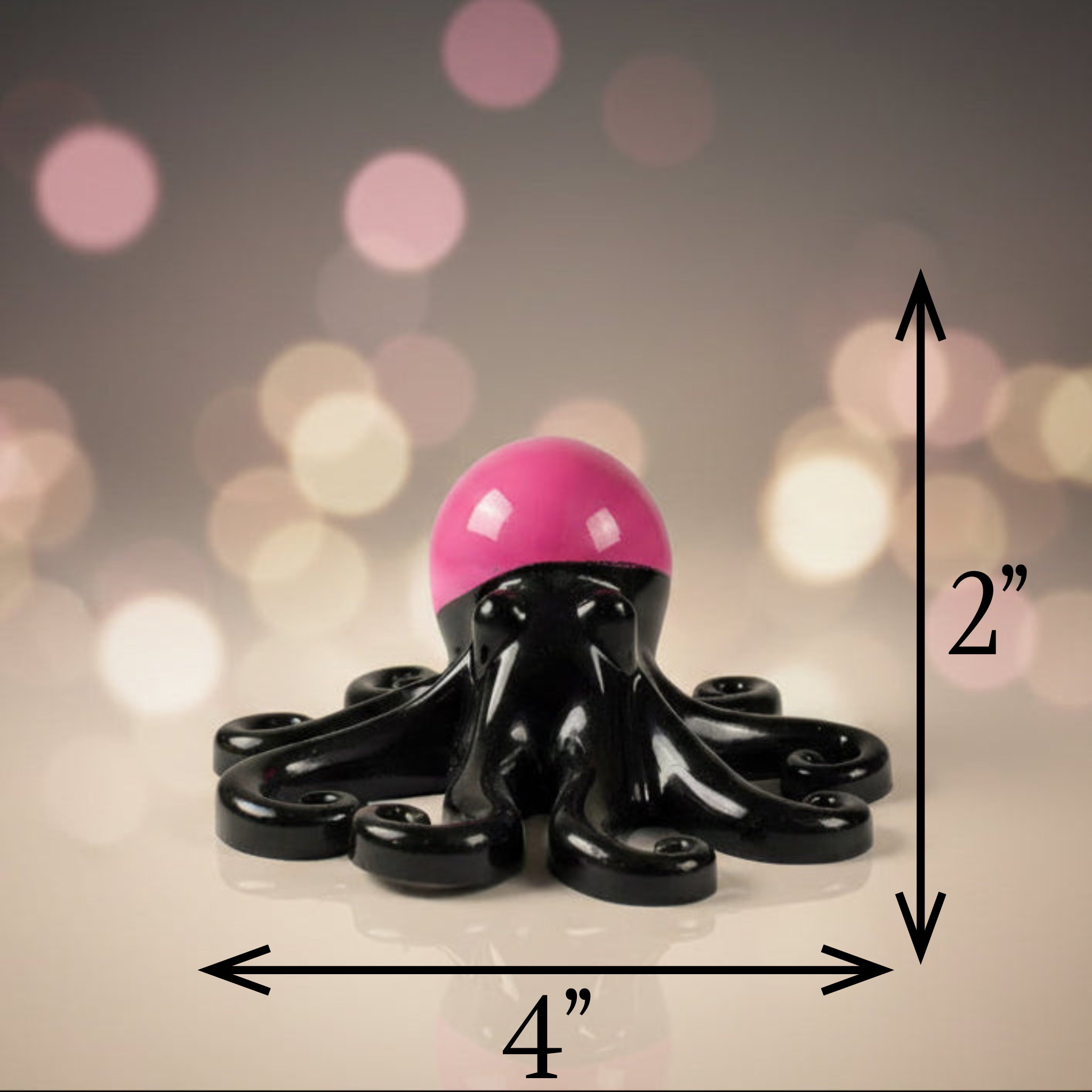 Glow in the dark resin octopus sculpture in black with pink glow head displayed on a blurred background to show measurements
