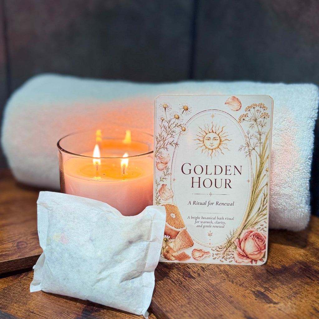 Candle, bath tea, and 'Golden Hour' ritual card on a wooden surface