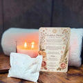 Candle, bath tea bag, and a ritual card titled 'The Golden Hour' on a wooden shelf by a bathtub.