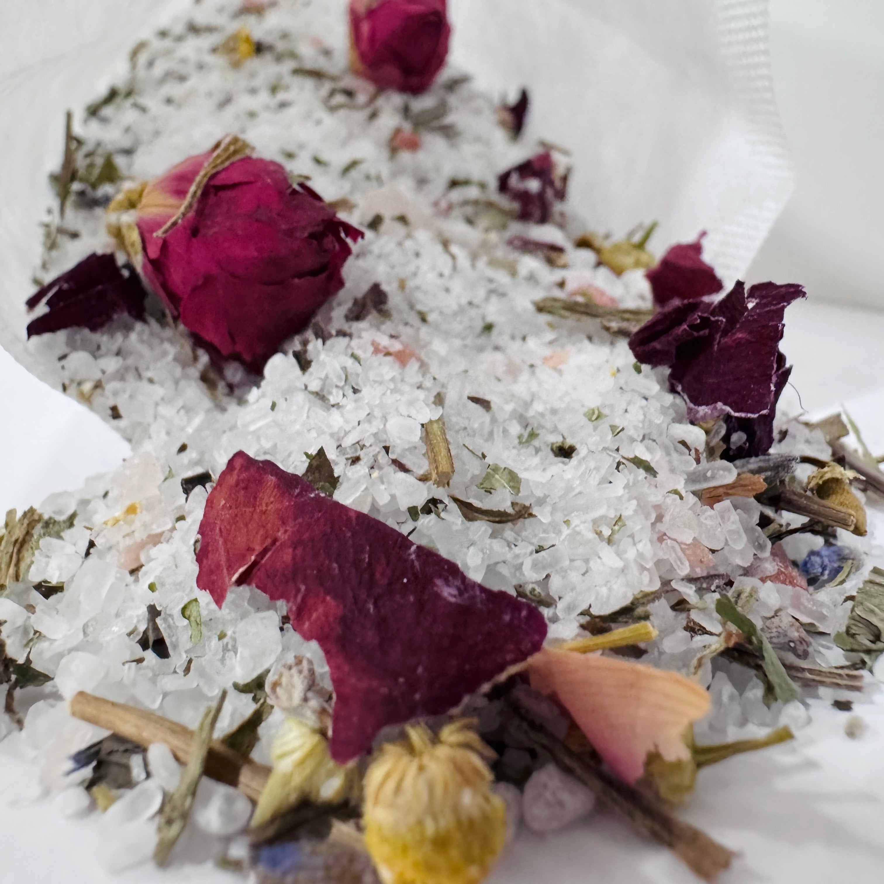 Salts with dried flowers and herbs on a white surface