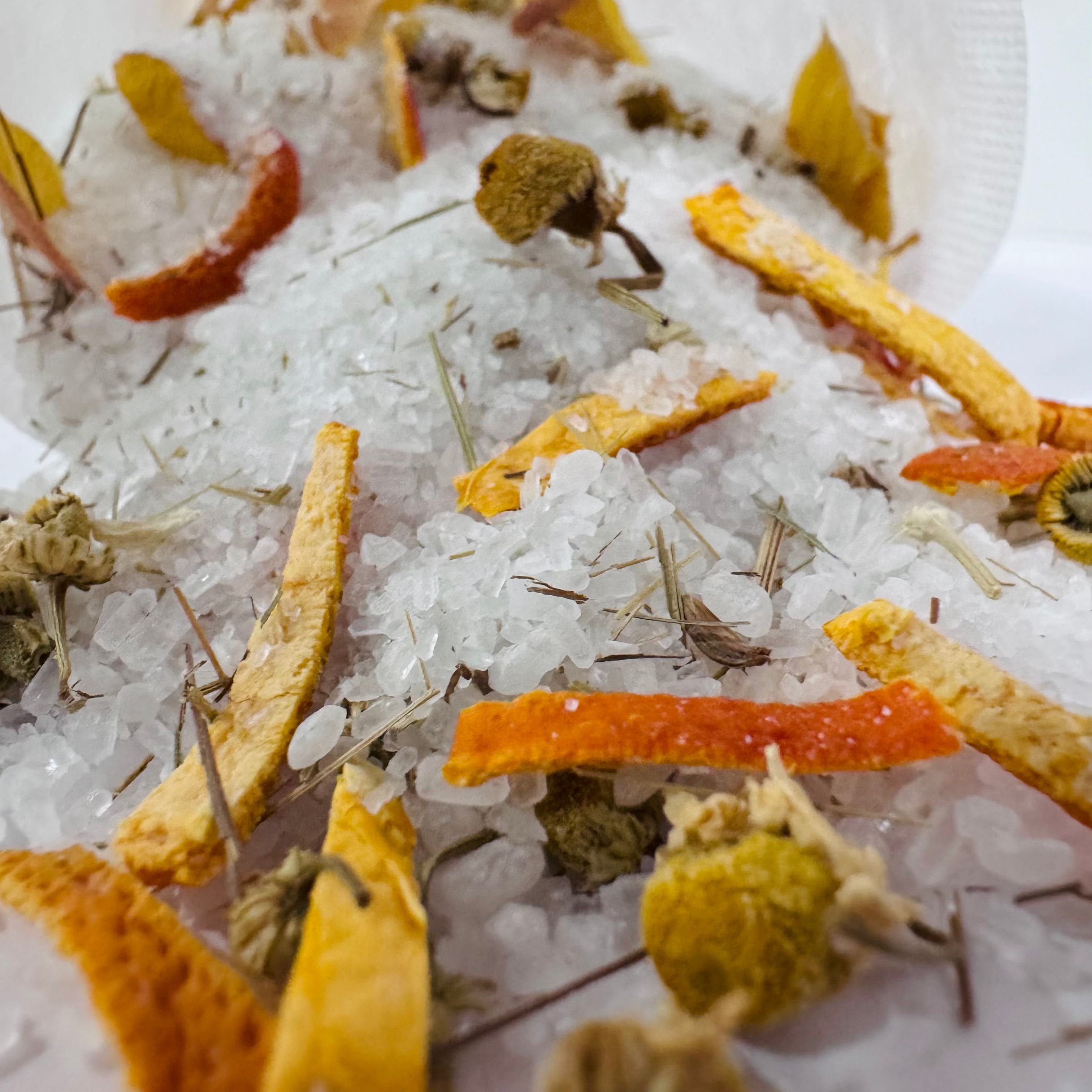 Dried orange peels and herbs on a bed of  salts with a white background