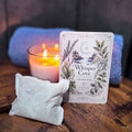 Candle with a 'Whisper Cove' packaging on a wooden surface